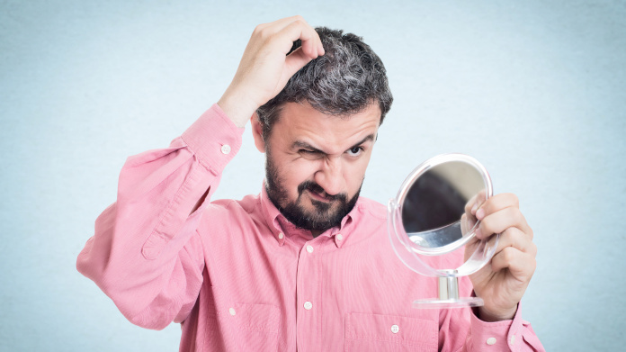 Man looking in the mirror seeing his hair going grey 